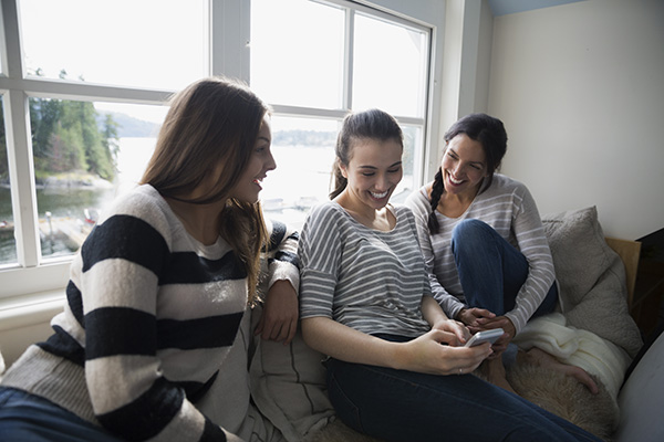 Group of three women seating on a couch laughing